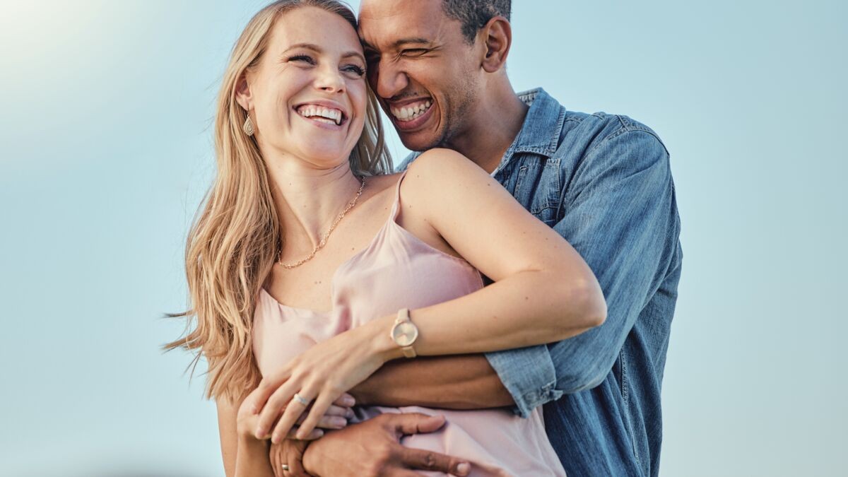 Un couple souriant, enlacé tendrement à l’extérieur, illustrant la complicité et la joie de célébrer leurs 4 ans de mariage, symbole des noces de cire.